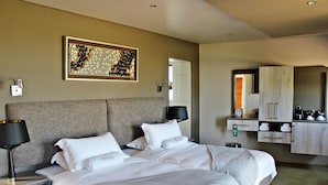 A modern hotel room with a large bed, bedside lamps, a mirror, and a wardrobe. - Thanda Tau - Hostel (Phumelela)