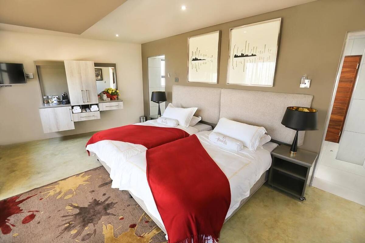 A modern bedroom with a large bed, bedside tables, a mirror, and artwork on the walls.