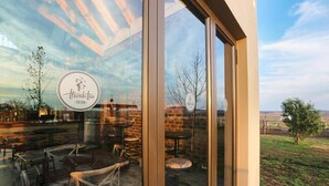 A restaurant with a glass wall, outdoor seating, and a logo on the glass. - Thanda Tau - Hostel (Phumelela)
