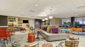 Un espace de détente moderne avec un canapé, des fauteuils colorés et une table à manger.