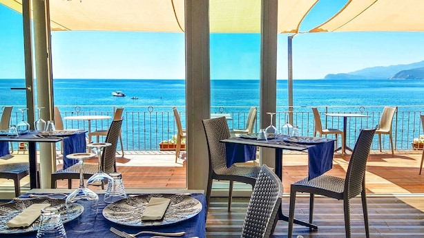An outdoor dining area with tables set for two, overlooking a clear blue sea. - Villaggio Innamorata - Villa Gisella (Capoliveri)
