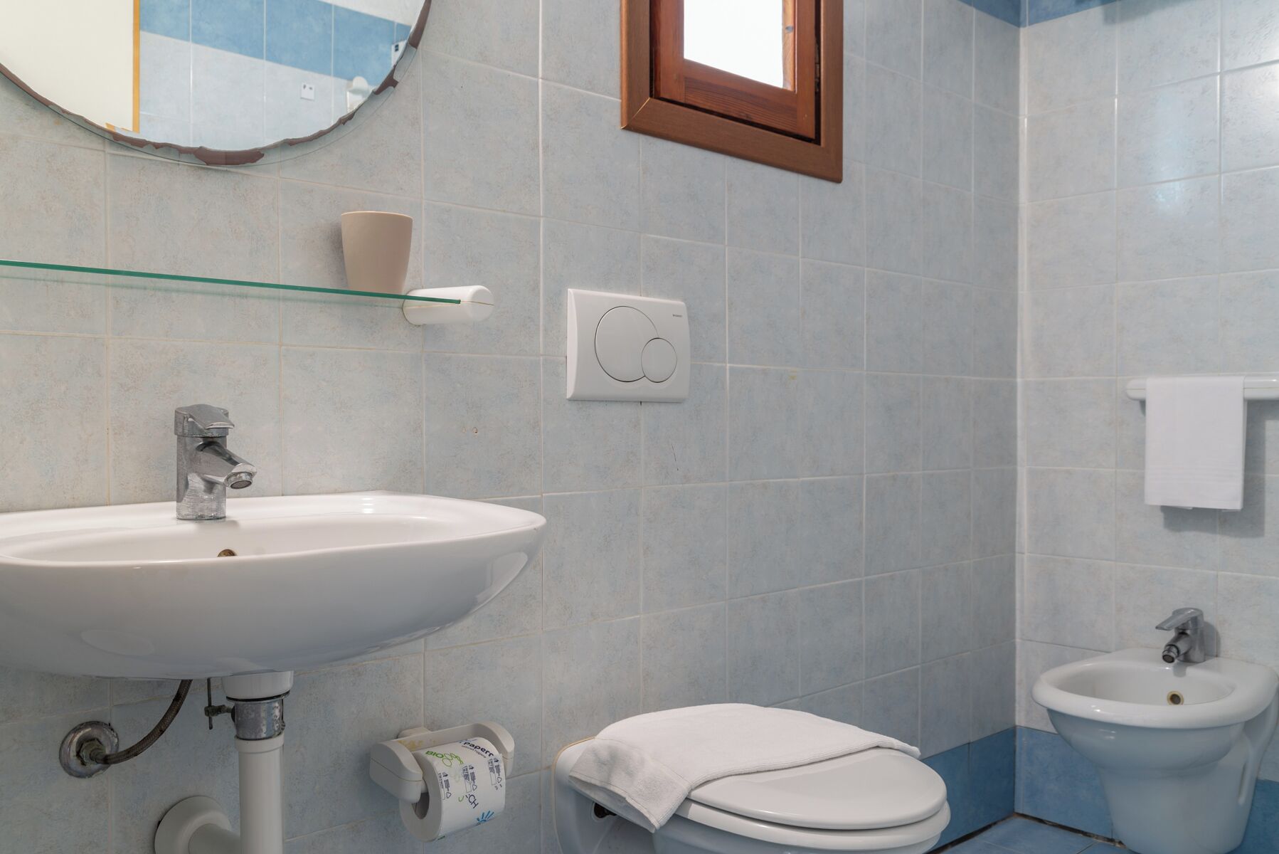 A bathroom with a sink, toilet, bidet, and a mirror.
