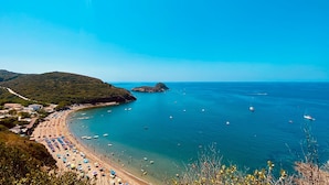 A coastal beach with clear blue waters, a sandy shore, and a hilly backdrop. - Villaggio Innamorata - Villa Gisella (Capoliveri)