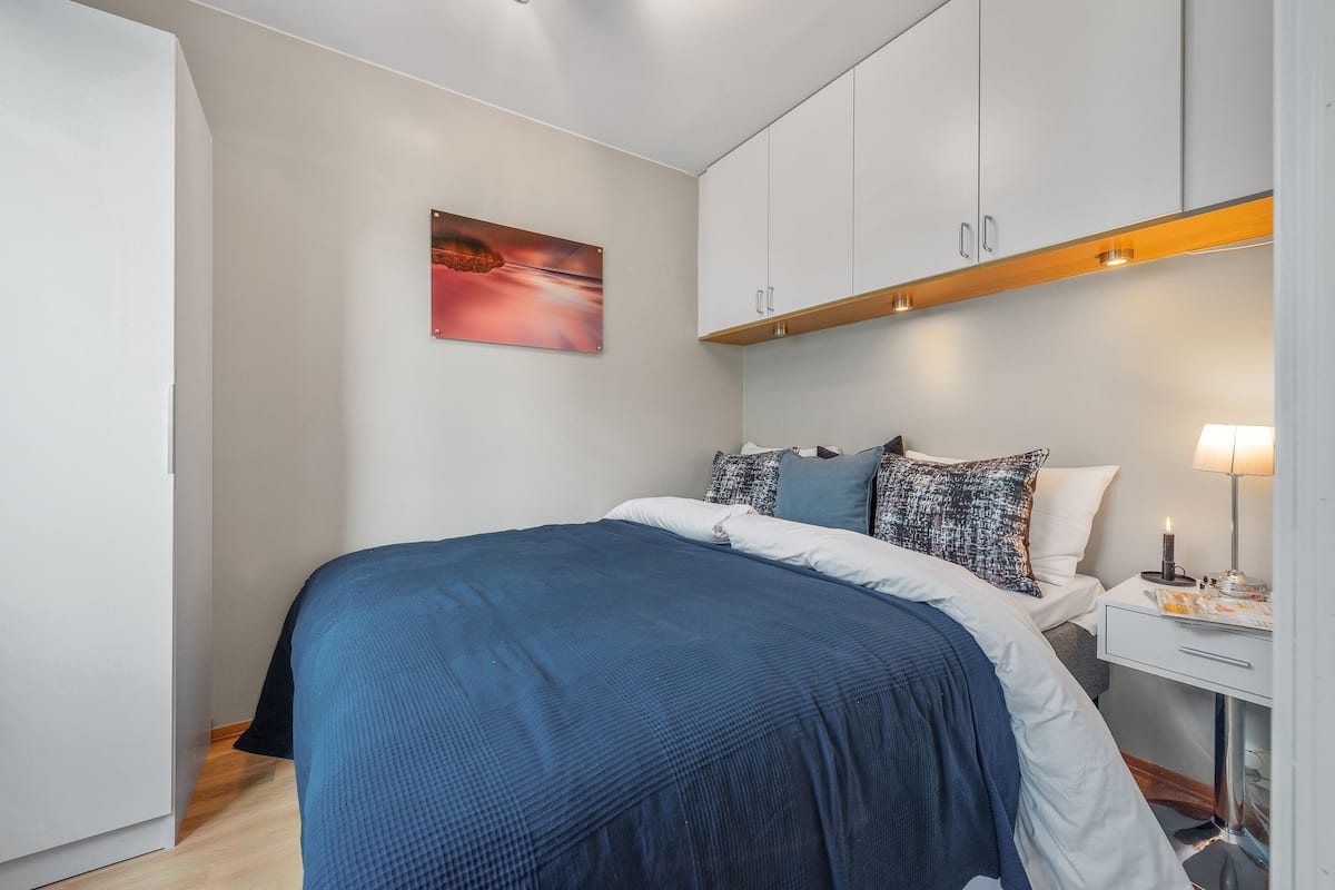 A bedroom with a bed, a nightstand, and a painting on the wall.