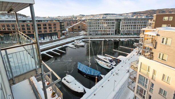 A marina with boats docked, a building with multiple floors, and a view of a cityscape in the background. - Bjørvika Apartments, Solsiden Area, Trondheim city center (Trondheim)
