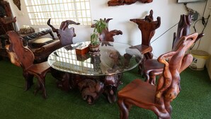 A round glass table surrounded by intricately carved wooden chairs. - WoodrootsBanteaychhmar (Siem Reap)