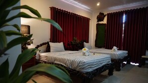 A hotel room with two beds, red curtains, a lamp, and a decorative mirror. - WoodrootsBanteaychhmar (Siem Reap)