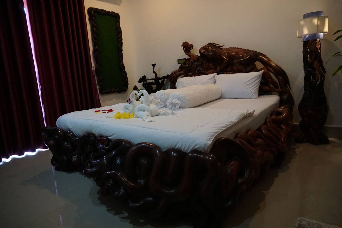 Ein Schlafzimmer mit einem einzigartigen hölzernen Kopfteil, einem Bett mit weißen Bettwäsche und einer dekorativen Blumenkomposition.