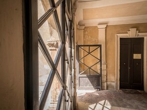 Experience the charm of this room with a high ceiling and herringbone-patterned floor, featuring a large window and a door with a black metal gate.