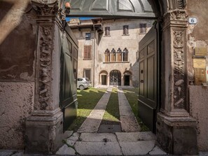 A courtyard with a paved path leading to a building entrance, surrounded by ornate stone columns. - Bright Apartments Verona - Cattaneo Historical (Verona)