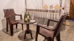 A dining area with a table and chairs, a bottle of wine, and a glass. - Luaya Beach (Tangalle)