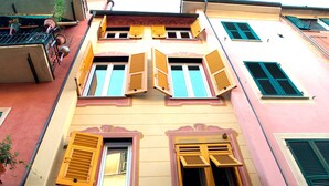 A multi-story building with yellow and pink facades, multiple windows with wooden shutters, and visible balconies. - Giramondo Room and Breakfast (Rapallo)