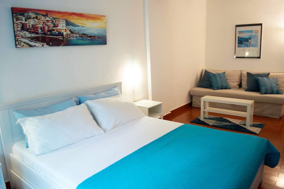 A bedroom with a bed, a nightstand, a bedside table, a sofa, and a coffee table.