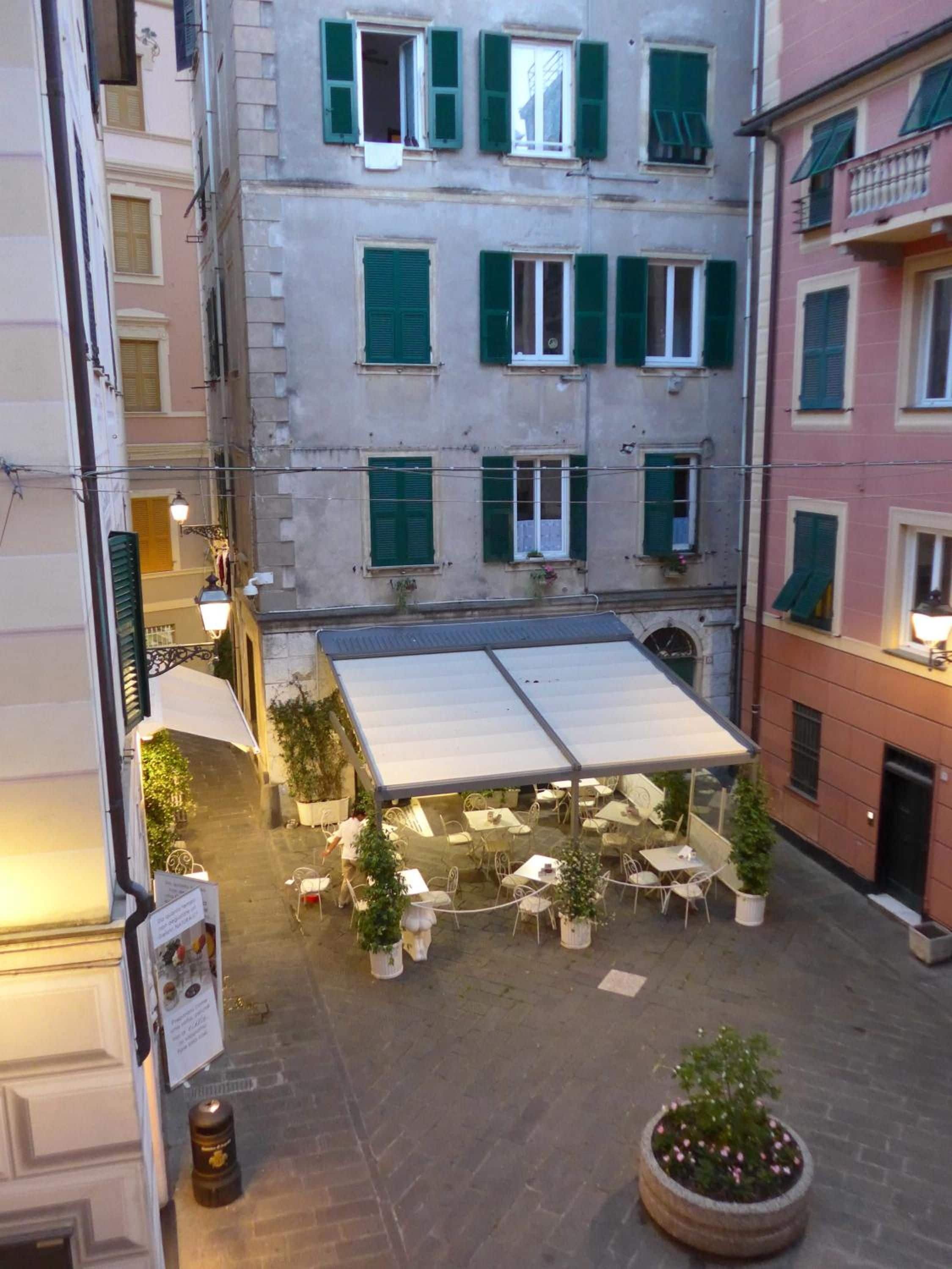 Un cortile con posti a sedere all'aperto, piante in vaso e una zona coperta.