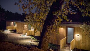A wooden cabin-style building with a staircase leading to a door, surrounded by trees and illuminated by exterior lighting. - Aloia Nature Alojamiento Forestal (Tui)