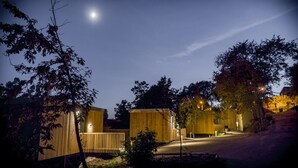 A series of wooden cabins with a dirt path leading to them, surrounded by trees and a clear night sky. - Aloia Nature Alojamiento Forestal (Tui)
