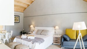 A modern bedroom with a large bed, bedside tables, a sofa, and a floor lamp. - Aloia Nature Alojamiento Forestal (Tui)
