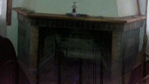 A room with a fireplace, a mirror, and a red cloth hanging above it. - Villa V (Lavreotiki)