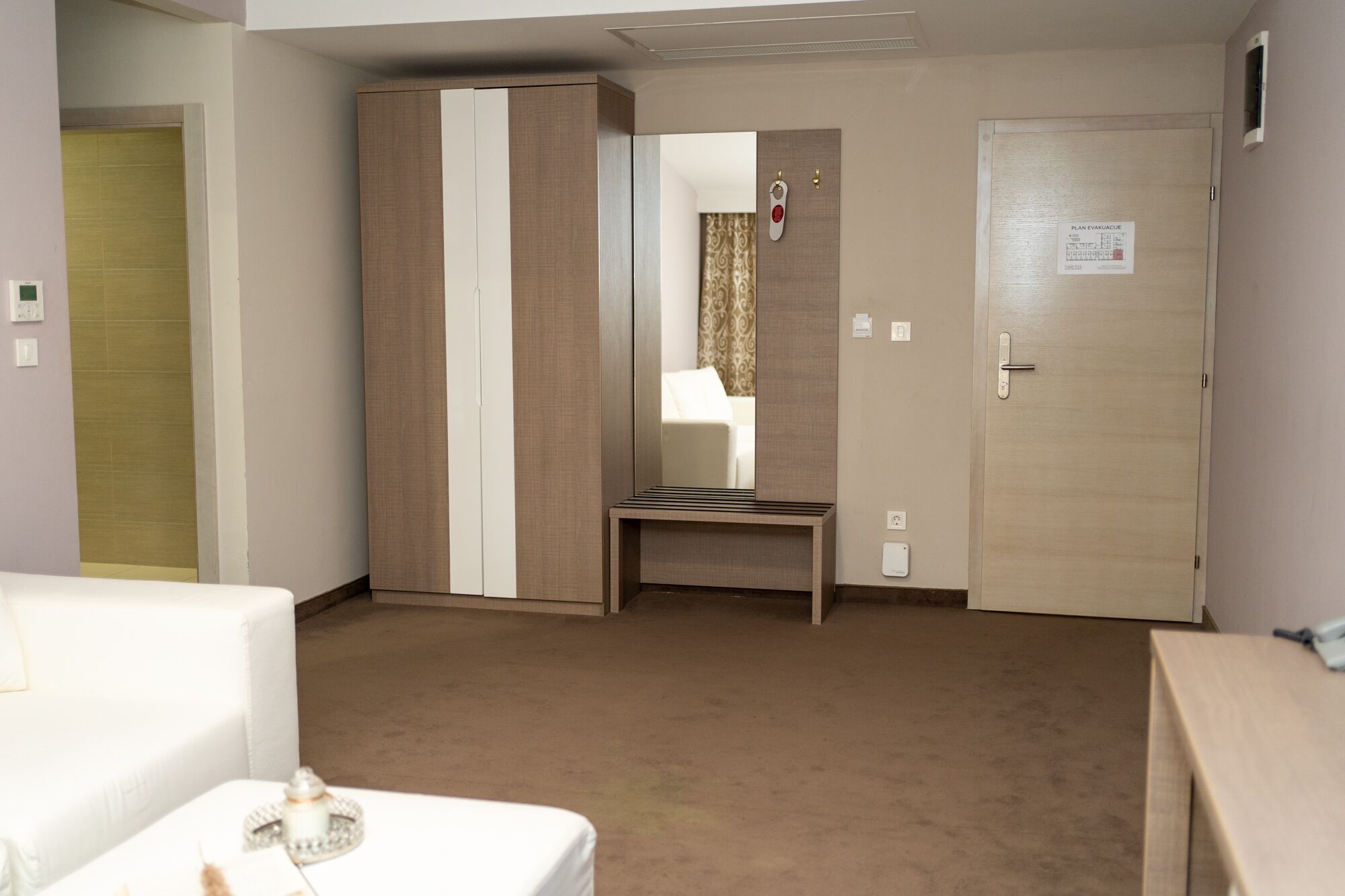 Ein Hotelzimmer mit Bett, Nachttisch, Schrank und einer Tür mit einem Schild.