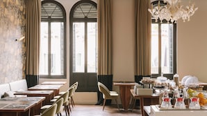 Un espace repas avec de longues tables, des chaises et un buffet où sont présentés différents plats.