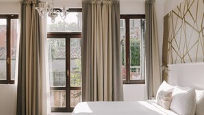 Un dormitorio con una cama grande, cortinas y vistas a través de un ventanal.