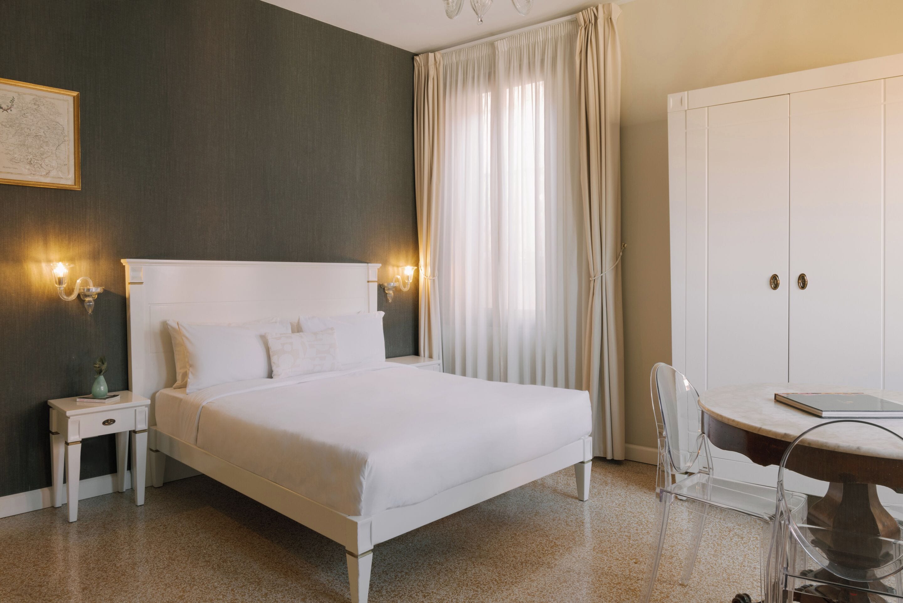 Quarto de hotel com cama, mesas de cabeceira, escrivaninha e guarda-roupa.