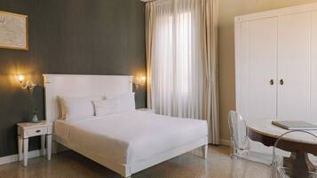 Quarto de hotel com cama, mesas de cabeceira, escrivaninha e guarda-roupa.