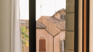 Una ventana con vista a un edificio de techo a ladrillo y una puerta con ventanal.