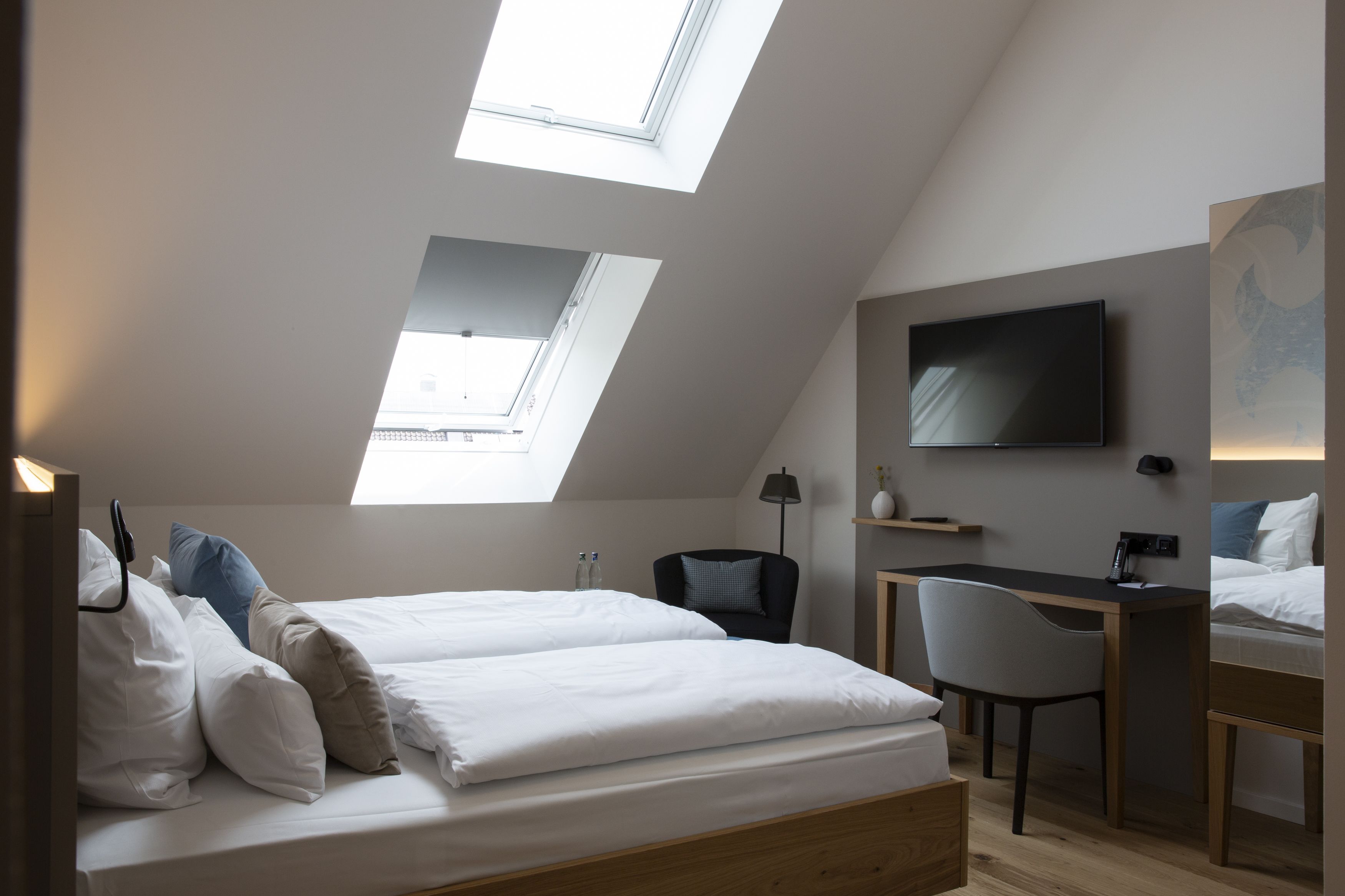 Un dormitorio moderno con tragaluces, una cama, un escritorio y un televisor.