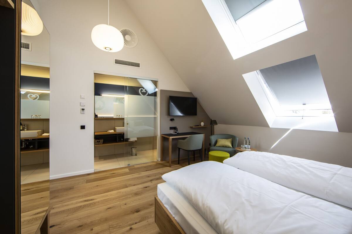 Ein modernes Schlafzimmer mit Dachfenster, Schreibtisch, Stuhl und Bett.
