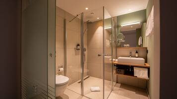 Ein modernes Badezimmer mit Duschkabine, Toilette und Waschtisch mit Spiegel und Waschbecken.