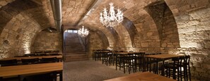 A stone-walled room with wooden tables and chairs, a staircase, and chandeliers. - Gasthaus und Hotel zum Löwen (Eimeldingen)