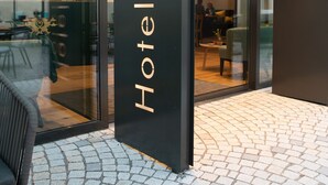 L’extérieur de l’hôtel Loewen présente un design moderne, avec une entrée en verre et un intérieur visible, comprenant des espaces aménagés pour se détendre.