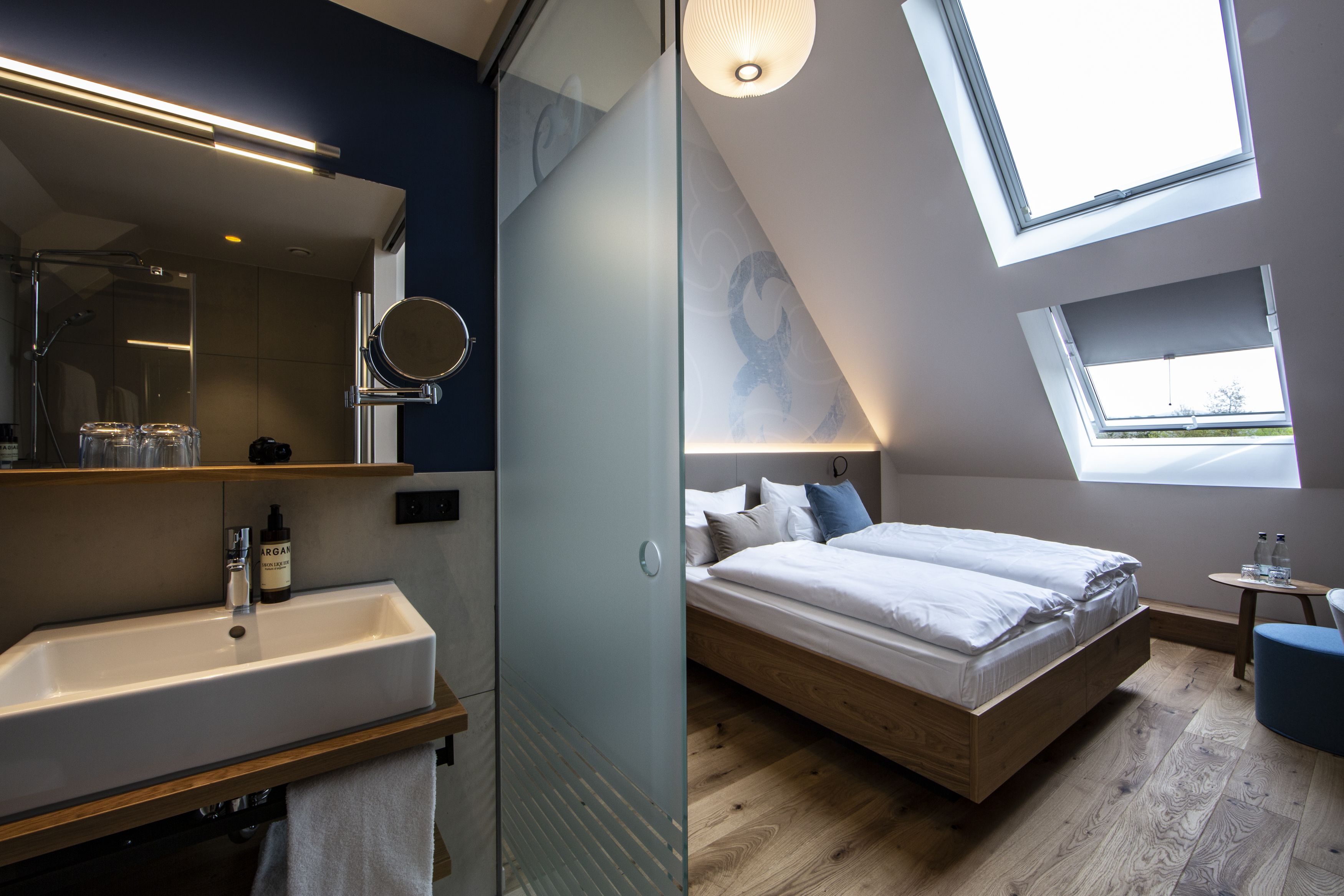 Un dormitorio moderno con tragaluces, una mesita de noche y un ventanal grande.