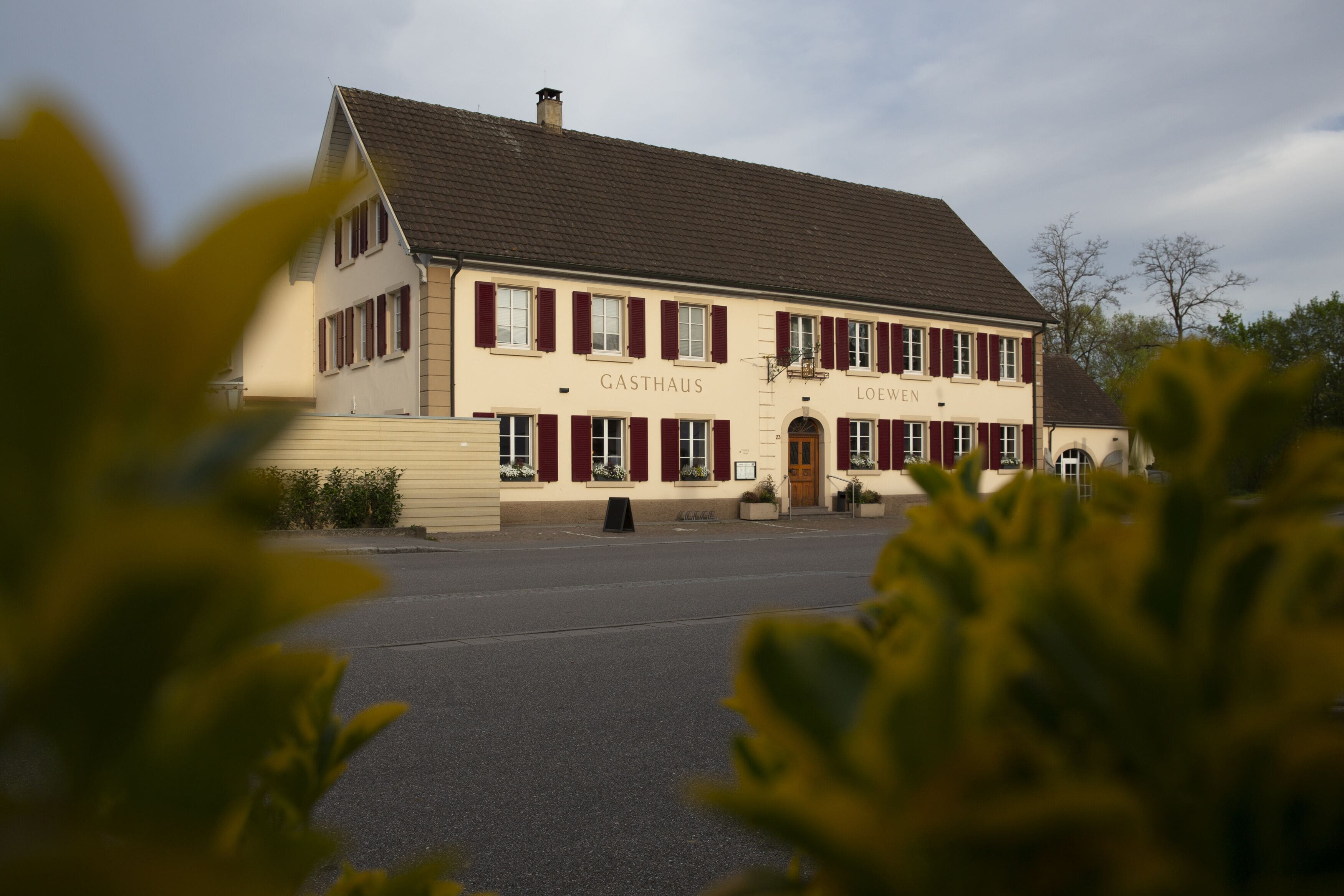 Un edificio de dos pisos con los nombres GASTHAUS y LOEWEN en la fachada.