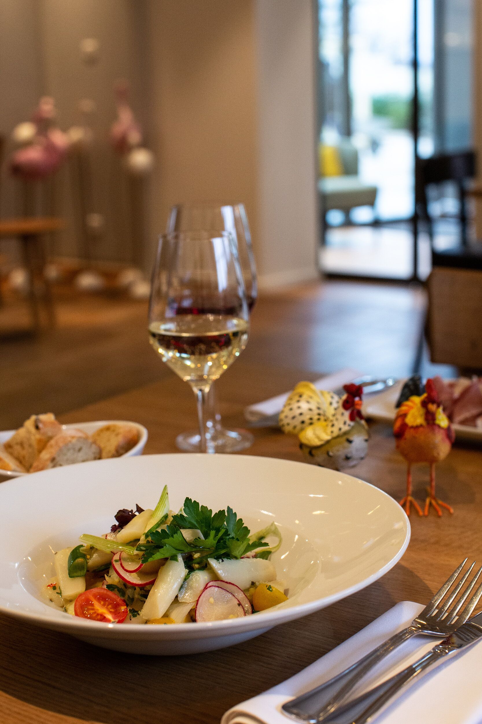 Une table à manger avec une assiette blanche remplie de nourriture, un verre à vin et une fourchette posée sur une serviette.
