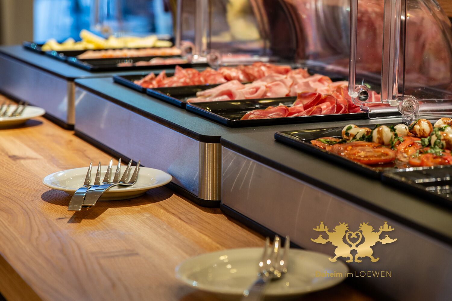 A buffet with various meats and a plate with utensils.