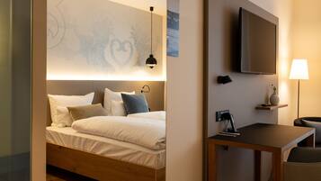 A hotel room with a bed, a desk, a TV, and a wall-mounted lamp.