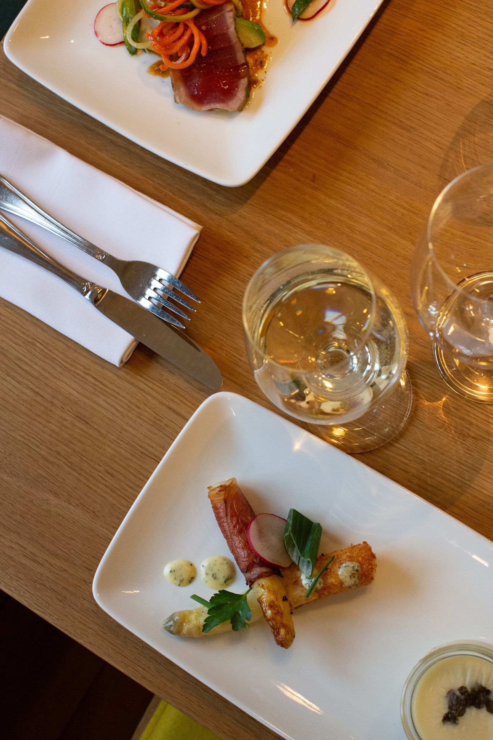 Una mesa de comedor con platos de comida, cubiertos y vasos.