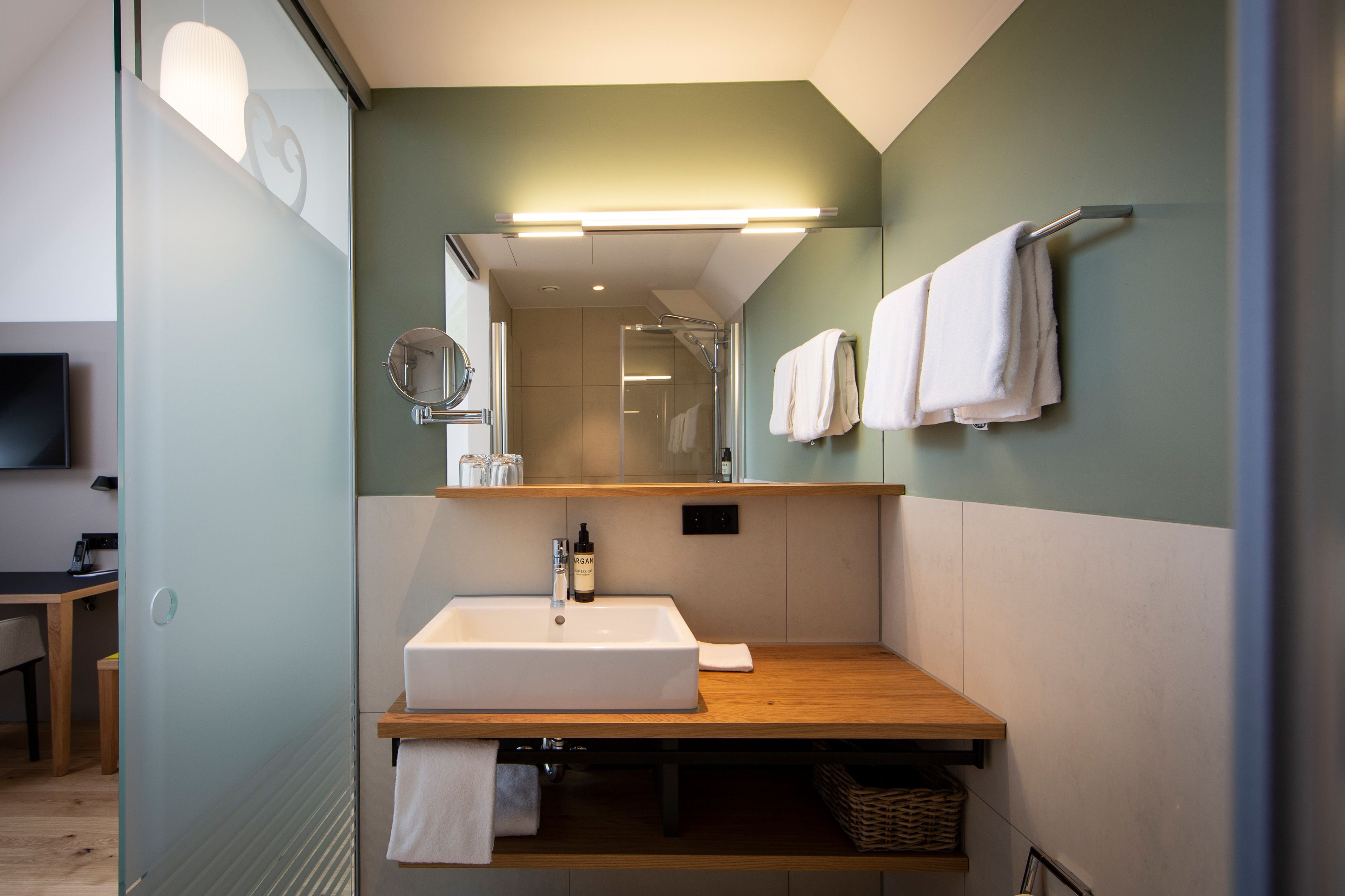 Un baño moderno con un tocador de madera, un espejo grande y un perchero para toallas.