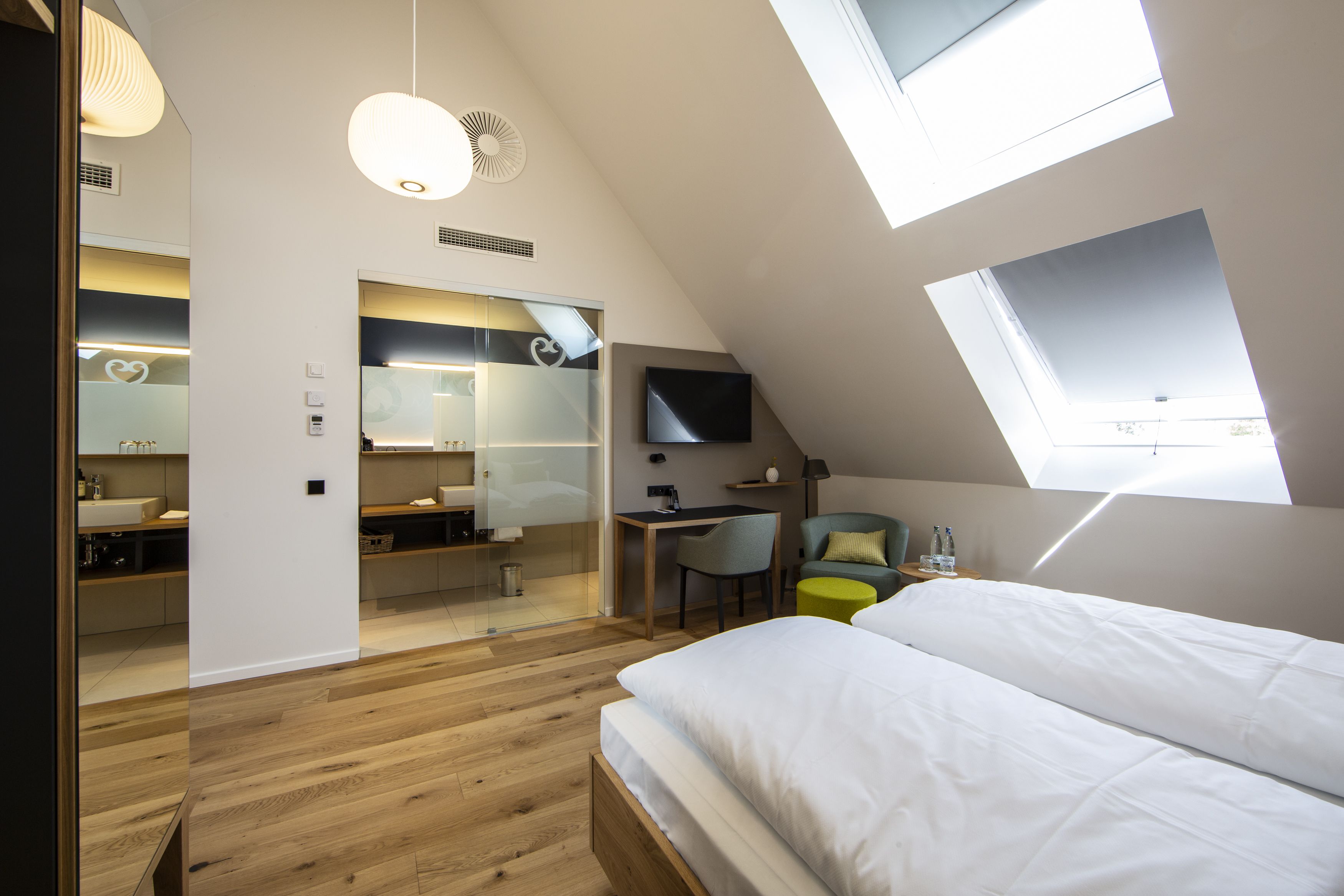 Ein modernes Schlafzimmer mit Oberlicht, Schreibtisch, Stuhl und Bett.