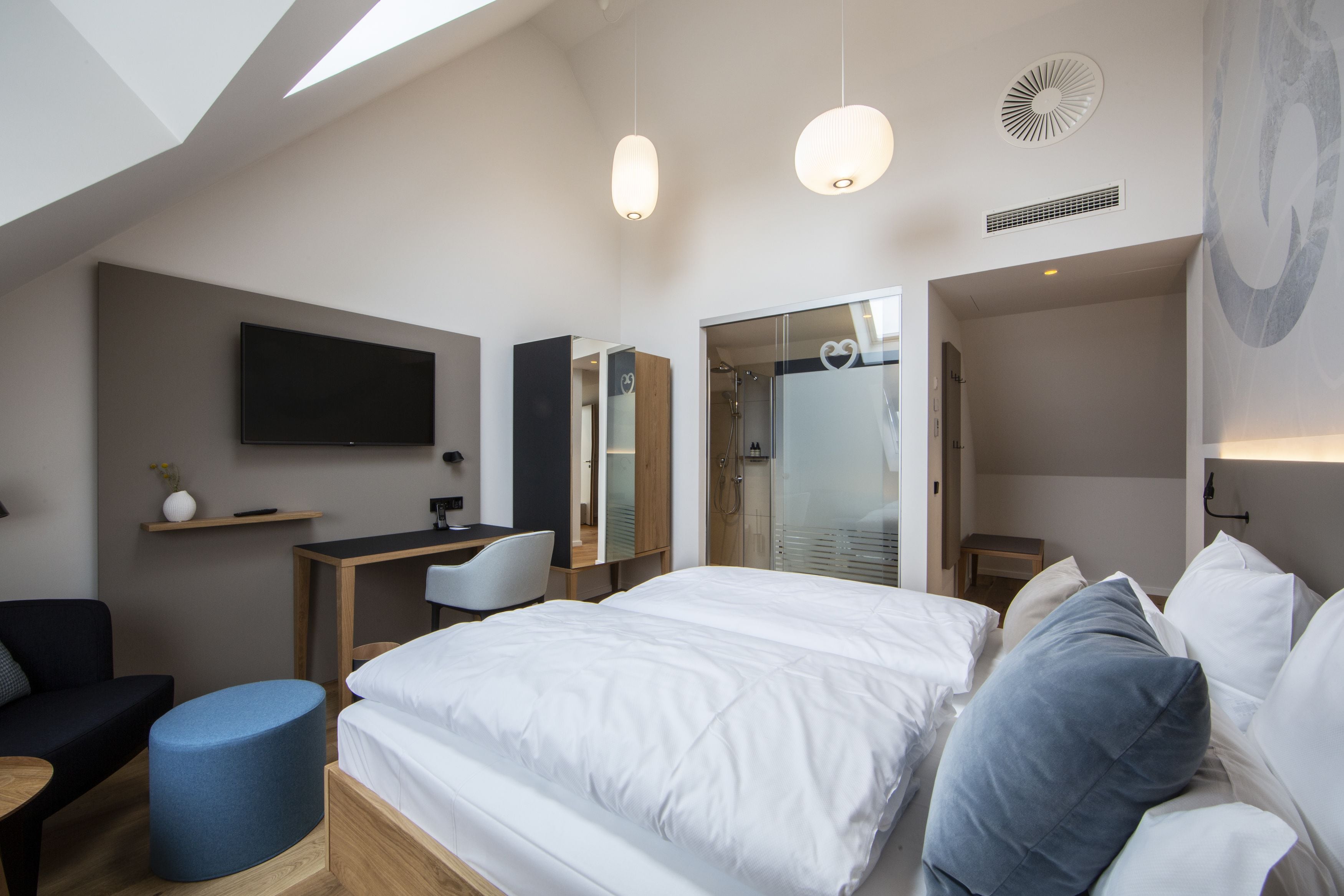 Een moderne hotelkamer met een groot bed, een bureau, een stoel, een televisie en een badkamer met een douchecabine.