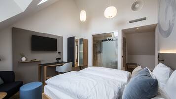 Een moderne hotelkamer met een groot bed, een bureau, een stoel, een televisie en een badkamer met een douchecabine.