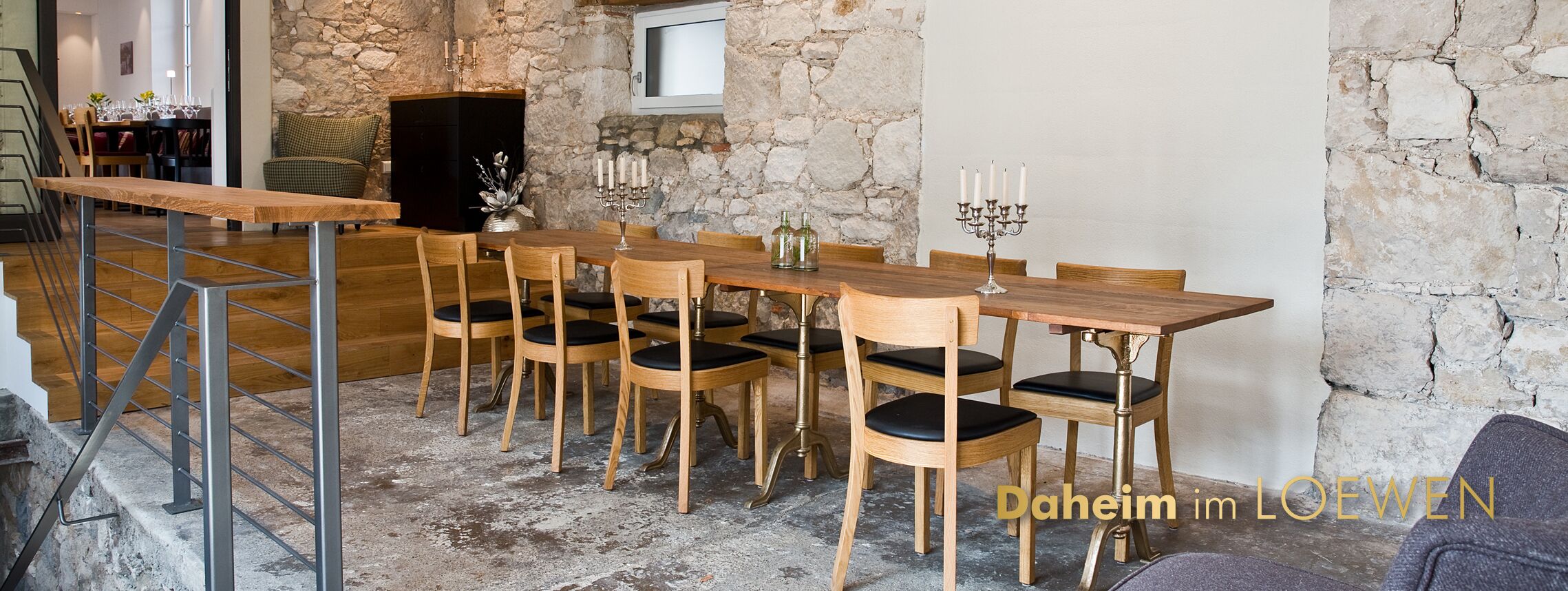 A dining area with a rustic stone wall, wooden table, and chairs.