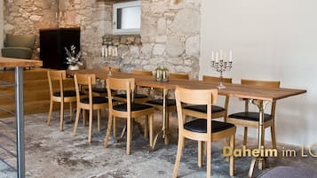 A dining area with a rustic stone wall, wooden table, and chairs.