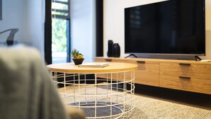 A modern living room with a round coffee table, a flat-screen TV, and a wooden cabinet. - Artel Apartment Hotel Melbourne (Brunswick)