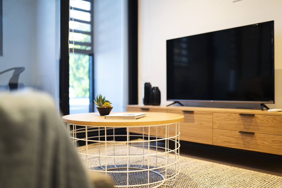 A modern living room with a round coffee table, a flat-screen TV, and a wooden cabinet.