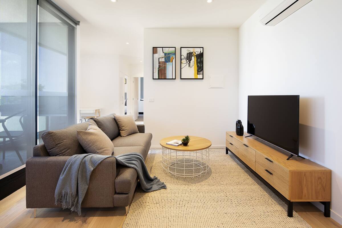 A modern living room with a sofa, coffee table, TV, and artwork on the wall.
