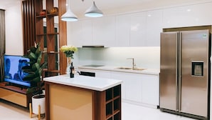 A modern kitchen with a central island, a built-in TV, and a stainless steel refrigerator. - LANDMARK PLUS RESIDENCES LUXURY SUITE (Ho Chi Minh City)