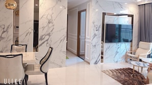 A modern living room with marble walls, a large flat-screen TV, and a chandelier. - LANDMARK PLUS RESIDENCES LUXURY SUITE (Ho Chi Minh City)